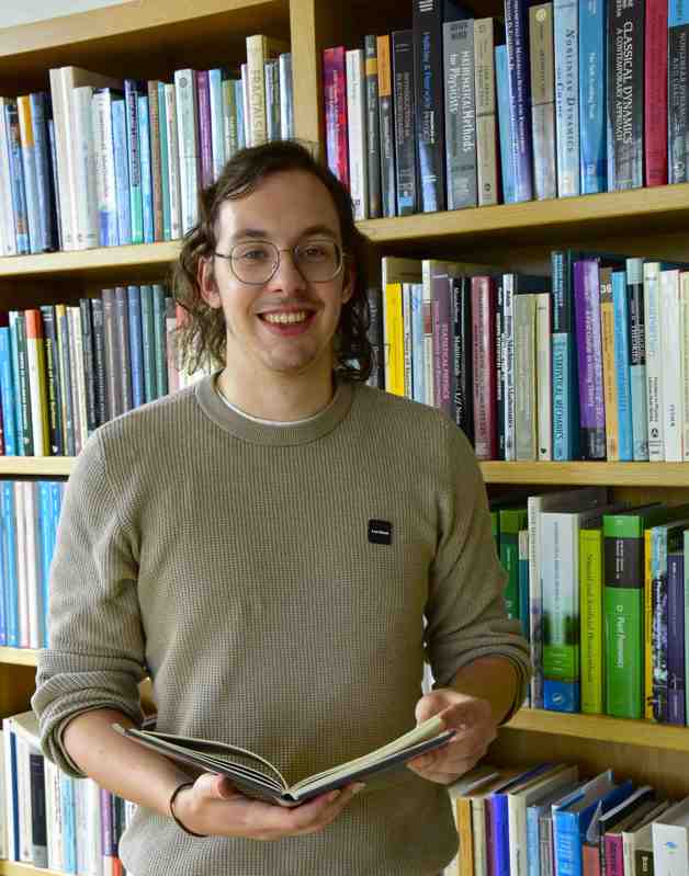 Niel Vandeweyer leest een boek in de bibliotheek.